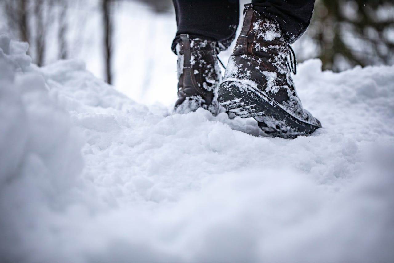 who-we-are Close-up of boots stepping in deep snow, showcasing winter footwear in a snowy landscape.